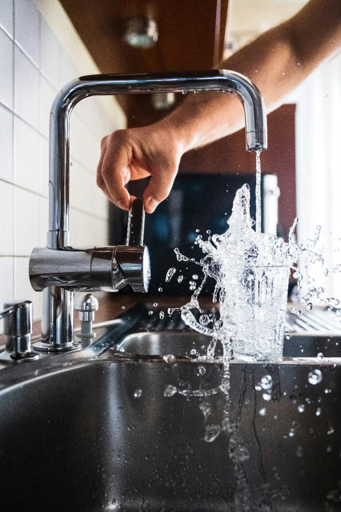 Modern kitchen faucet installation with water flowing into a glass during a remodel.