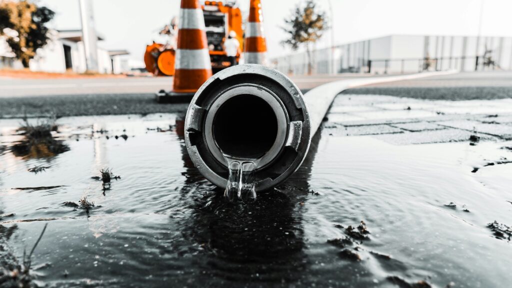 Water flowing out of large pipe onto pavement surface