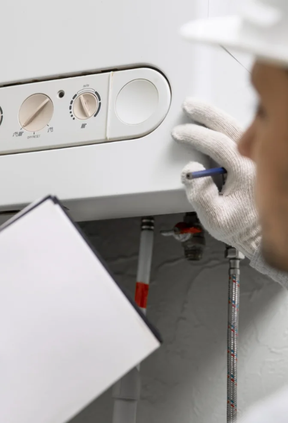 Technician checking water heater control panel with notebook in hand