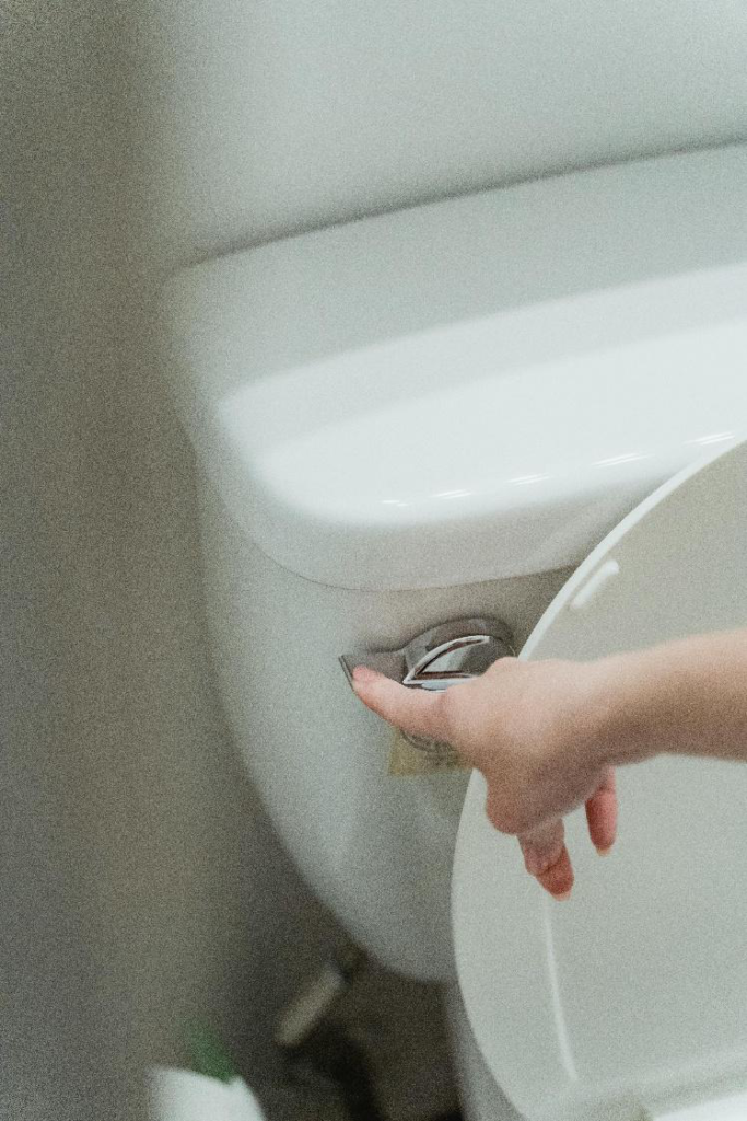  Hand pressing a toilet flush handle on a residential toilet tank