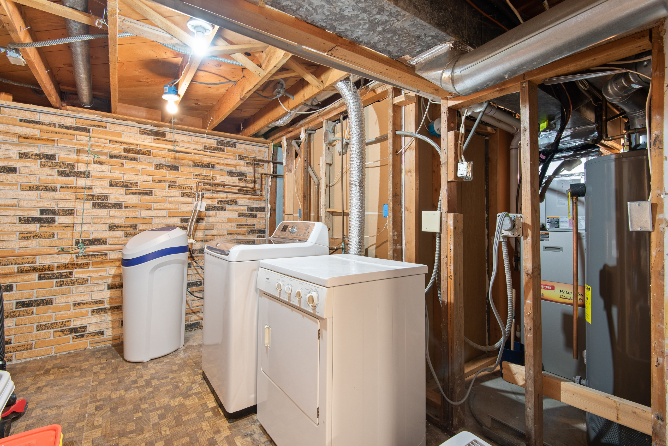 Tank water heater installed beside a washing machine in a residential laundry room