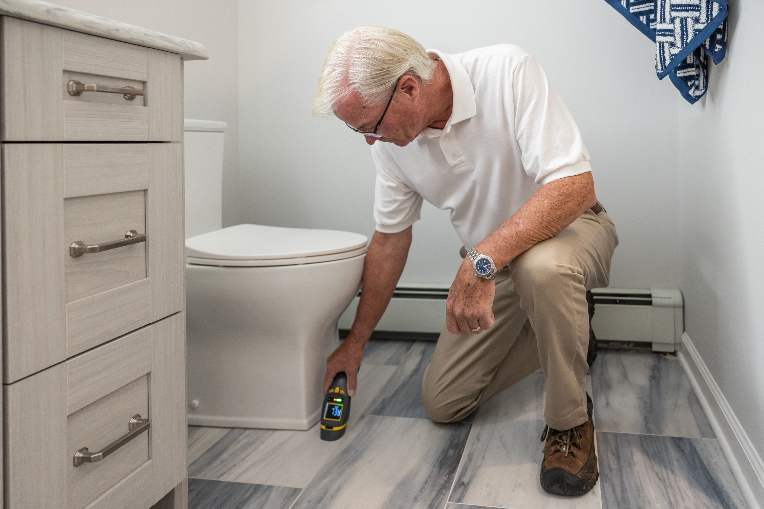 Technician inspecting a residential bathroom for maintenance concerns